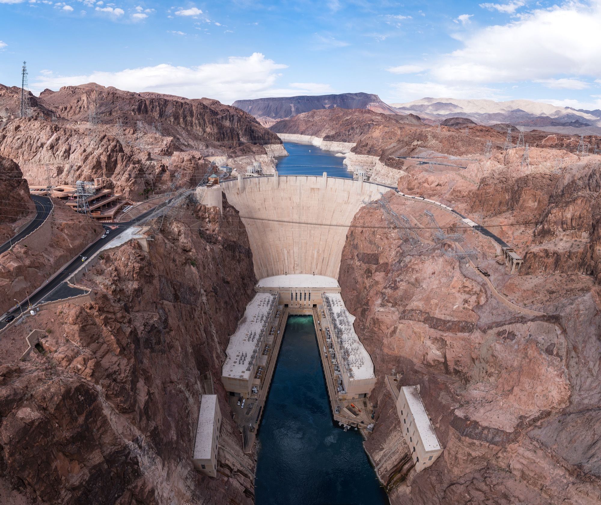Represa de arco en un cañón, con su casa de máquinas y el embalse detrás